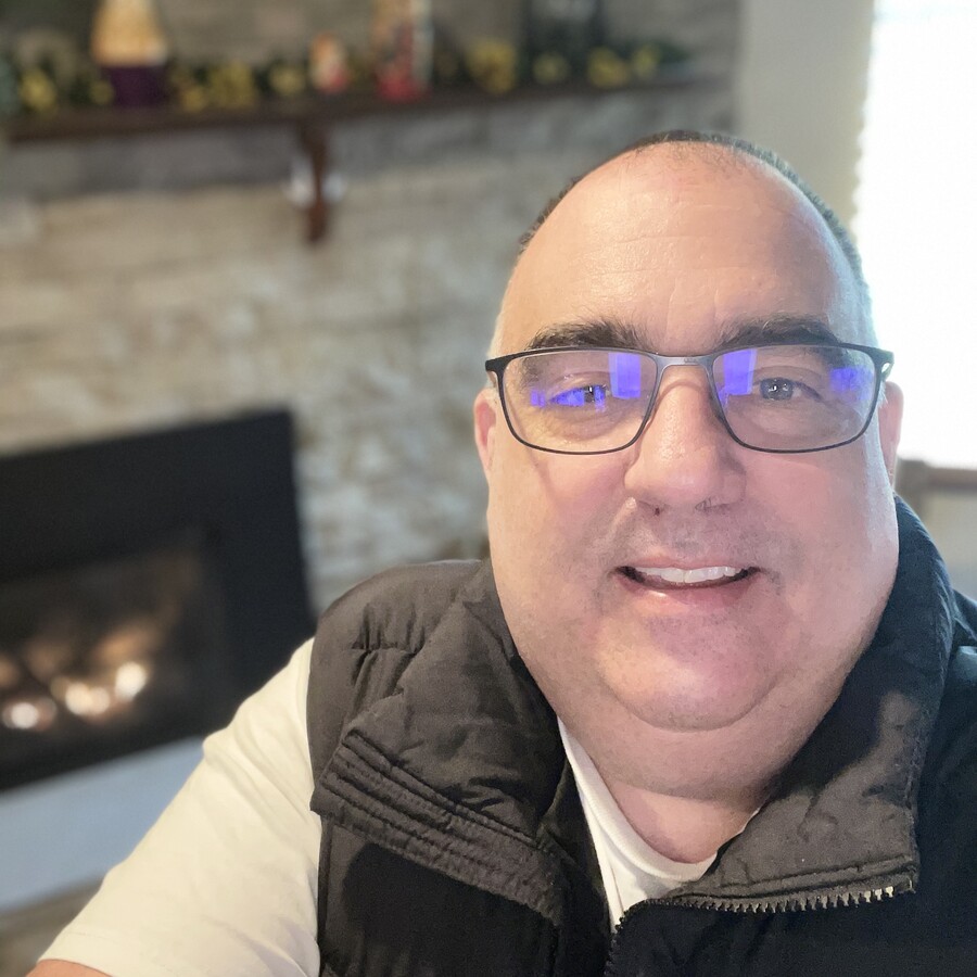 Brett Fullmer, smiling, wearing glasses and a black vest